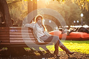 Beautiful woman sitting on a bench in sunset