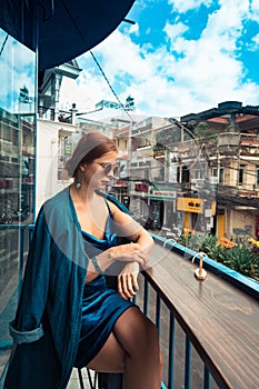 Beautiful woman sitting on cafe terrace. Panoramic street view of Da Lat city, little Paris of Vietnam