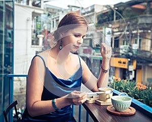 Beautiful woman sitting on cafe terrace. Panoramic street view of Da Lat city, little Paris of Vietnam