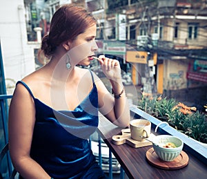 Beautiful woman sitting on cafe terrace. Panoramic street view of Da Lat city, little Paris of Vietnam