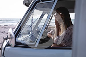Beautiful woman sitting in camper van at beach on a sunny day