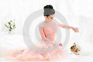 Beautiful woman sitting on the floor playing with a rabbit.