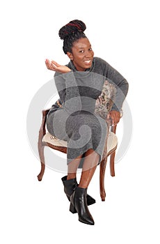 Beautiful woman sitting in a gray dress in an old chair