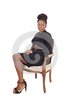 Beautiful woman sitting in a gray dress in an old chair