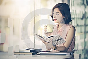 Beautiful woman sitting at her desk holding cup of coffee
