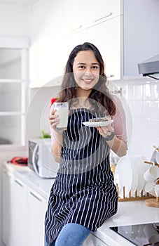 Beautiful woman sitting on kitchen tabl and drinking milk in kitchen morning photo