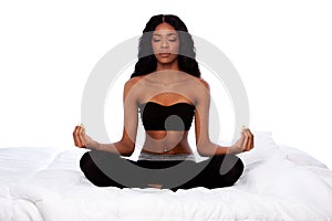 Beautiful woman sitting in lotus yoga pose on bed