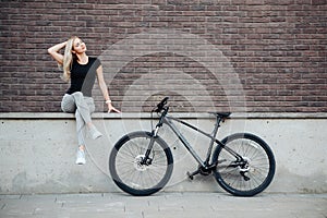 Beautiful woman sitting near bike after morning cycling