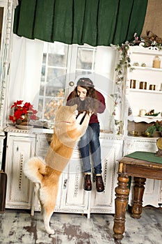 Beautiful woman sitting retro tree dresser. hugs, cuddles with her akita inu dog