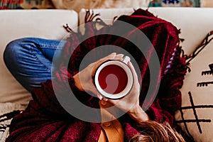 beautiful woman sitting on the sofa, enjoying a cup of tea. cute golden retriever dog besides. lifestyle indoors. close up view