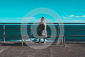 Beautiful woman sitting on wooden bench enjoying the beautiful sea