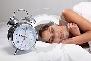 Beautiful woman sleeping with alarm clock nearby