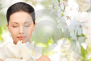 Beautiful woman smelling flowers with closed eyes
