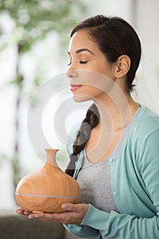 beautiful woman smelling steam from aroma diffuser