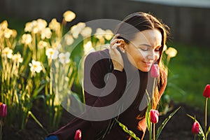 Beautiful woman smelling the tulips planted.