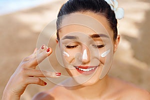 Beautiful Woman smile applying sun cream on face. Skin and  Body  care. Sun protection