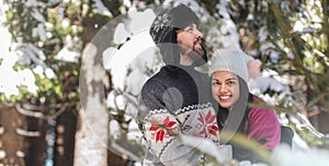 Beautiful woman smiling and hugging man in winter forest