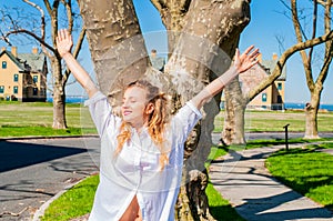 Beautiful woman smiling joyful with arms up in the park.