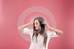 Beautiful woman  smiling looking aside with smartphone in hands enjoying favorite music, via wireless headphones over pink backgro