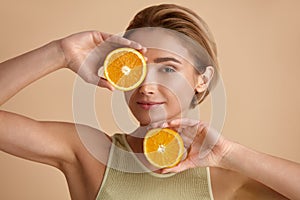 Beautiful woman smiling with orange fruit. Woman recommended vitamin for skin