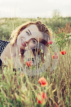 Beautiful woman is smiling and posing in poppy flowers field