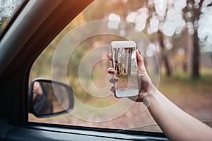 Beautiful woman smiling while sitting on the passenger seats in the car. Girl is using a smartphone She makes a photo of