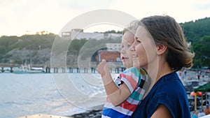 Beautiful woman with son looking over horison at the sea, windy weather