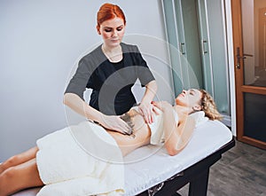 Beautiful woman in spa salon getting mud body massage