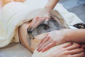 Beautiful woman in spa salon getting mud body massage
