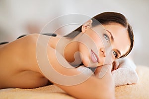 Beautiful woman in spa salon with hot stones