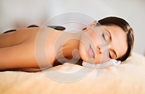 Beautiful woman in spa salon with hot stones