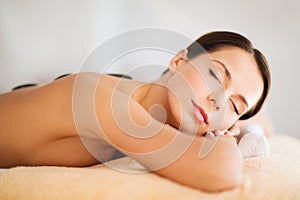 Beautiful woman in spa salon with hot stones