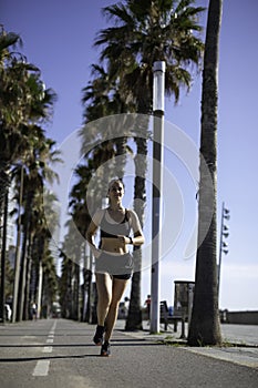 Beautiful woman in sport clothes running on the bike lane at the seafront in Barcelona & x28;SPAIN