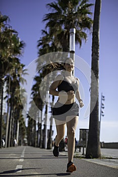 Beautiful woman in sport clothes running on the bike lane at the seafront in Barcelona & x28;SPAIN