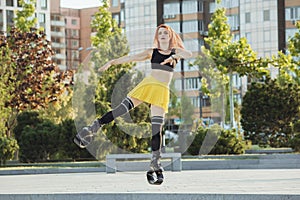 Beautiful woman in sportswear jumping in a kangoo jumps shoes at the street on summer`s sunny day