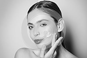 Beautiful woman spreading cream on her face. Skin cream concept. Facial care for female. Keep skin hydrated regularly