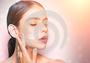Beautiful woman spreading cream on her face. Skin cream concept. Facial care for female. Keep skin hydrated regularly photo