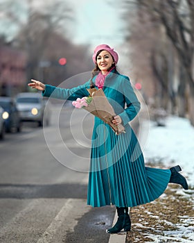 Beautiful woman with spring tulips flowers bouquet at city street. Happy portrait of girl smiling with pink tulip