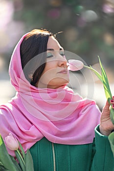 Beautiful woman with spring tulips flowers bouquet at city street. Happy portrait of girl smiling with pink tulip