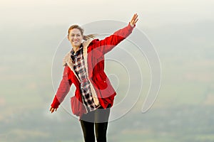 Beautiful woman stand near cliff with background of grass field and rural village area in view on the mountain with warm light of