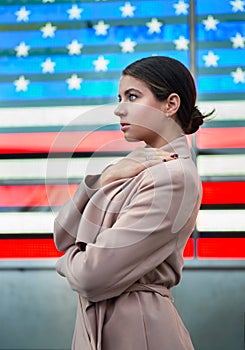 Beautiful woman standing in front of american flag and looking to the side. People nation patriotism concept