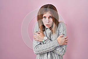 Beautiful woman standing over pink background shaking and freezing for winter cold with sad and shock expression on face