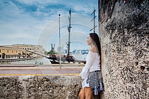 Beautiful woman standing at the walls of Cartagena de Indias looking to the bay