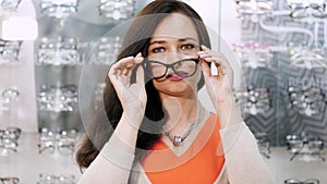 beautiful woman staring at camera. Portrait of smiling female customer wearing spectacles in optical store, in an