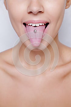 Beautiful woman sticking out her tongue and showing young piercing