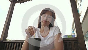 Beautiful woman stirring a wooden spoon hot drink in a cafe on the street. a glass of coffee is on the table, a girl is