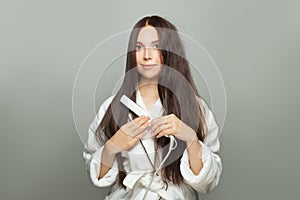 Beautiful woman straighten her hair with straightener on white background. Haircare concept photo