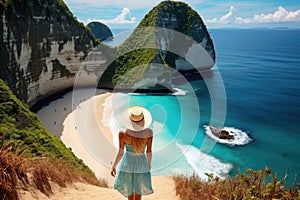 Beautiful woman in a straw hat on the beach of Nusa Penida, Indonesia, rear view of a Woman walking at Kelingking Beach in Nusa