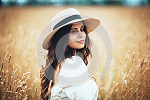 Beautiful woman in straw hat among field grass