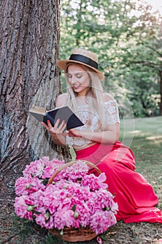 Beautiful woman on straw hat reading a book in the garden